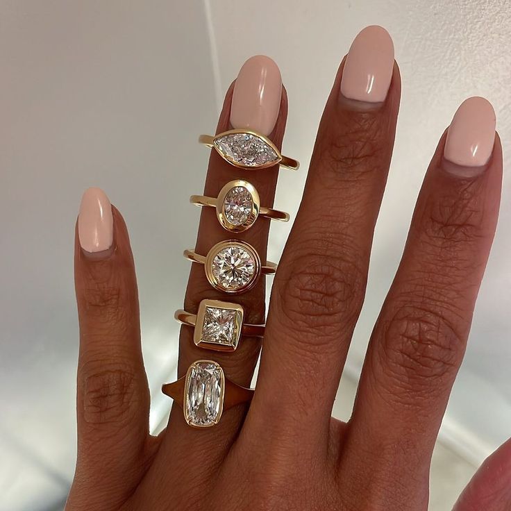 a woman's hand with five different rings on it and one diamond ring in the middle