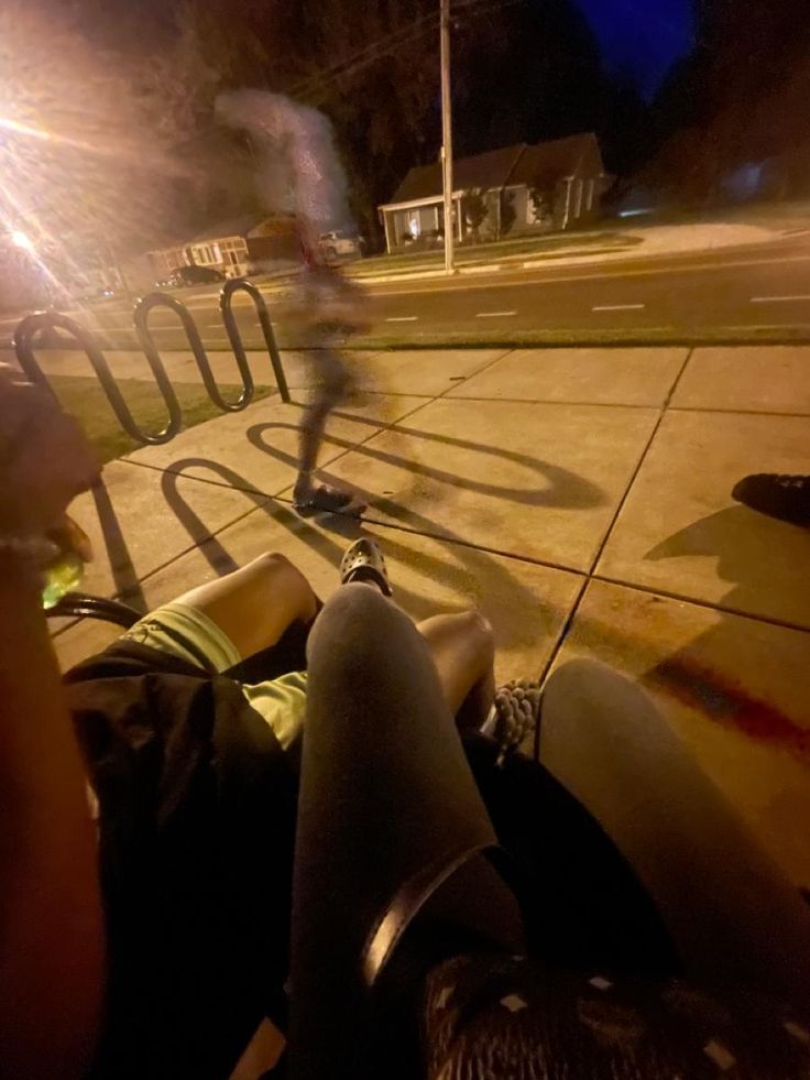 a man riding a skateboard down the side of a road at night with his shadow on the ground