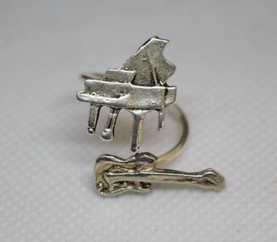 I handcrafted this ring using a beautiful silver plated over brass piano, a silver plated guitar and a silver plated wire ring base. The ring is adjustable and fits a size 5 - 9.It comes in a gift box.Extra little GIFT included separately with the packaging!Please contact me for any questions or alterations. I will be more than happy to help you.For more jewelry designs, you can visit my other shop at: www.etsy.com/shop/mastaartshopShipping cost includes unique tracking number for tracking your Vintage Silver Jewelry For Concerts, Adjustable Silver Jewelry For Concert, Adjustable Silver Jewelry For Concerts, Silver Music-themed Rings For Gifts, Music-themed Silver Rings As Gifts, Music-themed Silver Ring As A Gift, Music-themed Silver Rings For Gifts, Music-themed Silver Rings For Gift, Music Ring