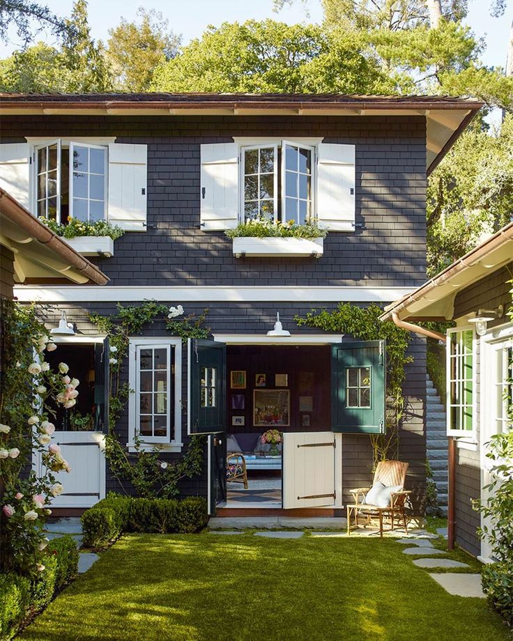 a house with white shutters on the windows and green grass in front of it