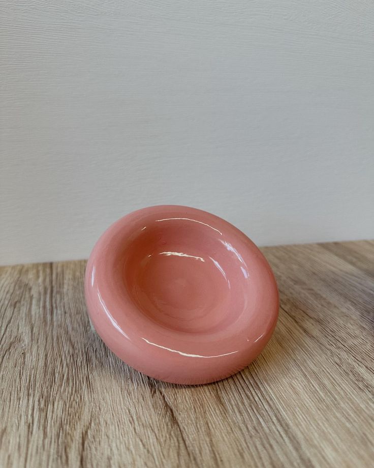 a pink bowl sitting on top of a wooden table