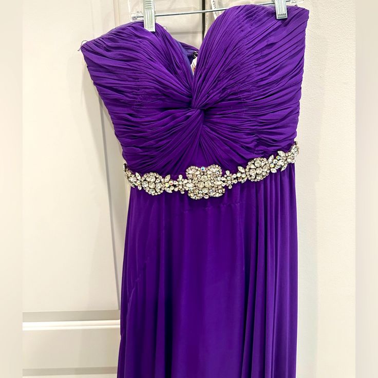 Royal Purple Evening Gown With Beaded Belt By Jovani Purple Evening Gown With Pleated Bodice, Purple Floor-length Evening Dress With Pleated Bodice, Purple Wedding Evening Dress With Pleated Bodice, Purple Strapless Evening Dress With Sweep Train, Elegant Purple Maxi Dress With Sweetheart Neckline, Purple Strapless Evening Dress For Bridesmaid, Strapless Purple Bridesmaid Evening Dress, Elegant Purple Strapless Dress For Prom Season, Strapless Purple Evening Dress For Wedding