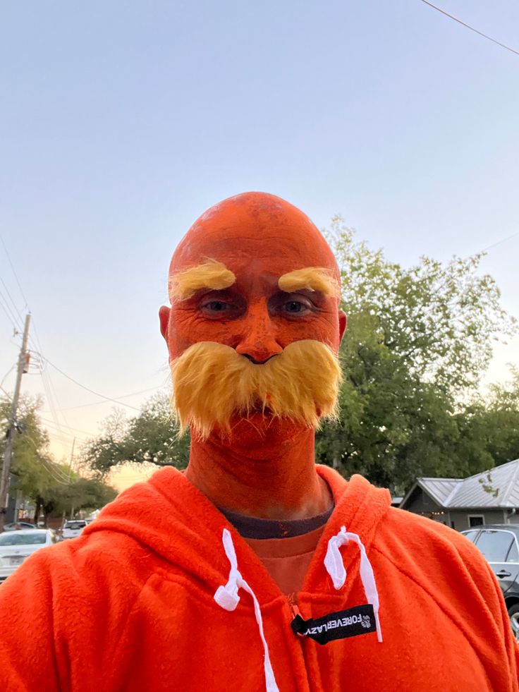 a man with a fake moustache on his face is wearing a red hoodie