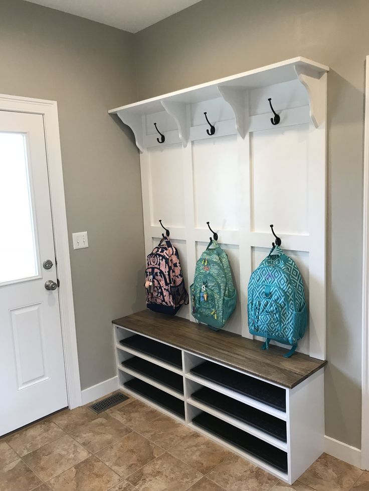 three bags are hanging on the back of a coat rack in a room with tile flooring