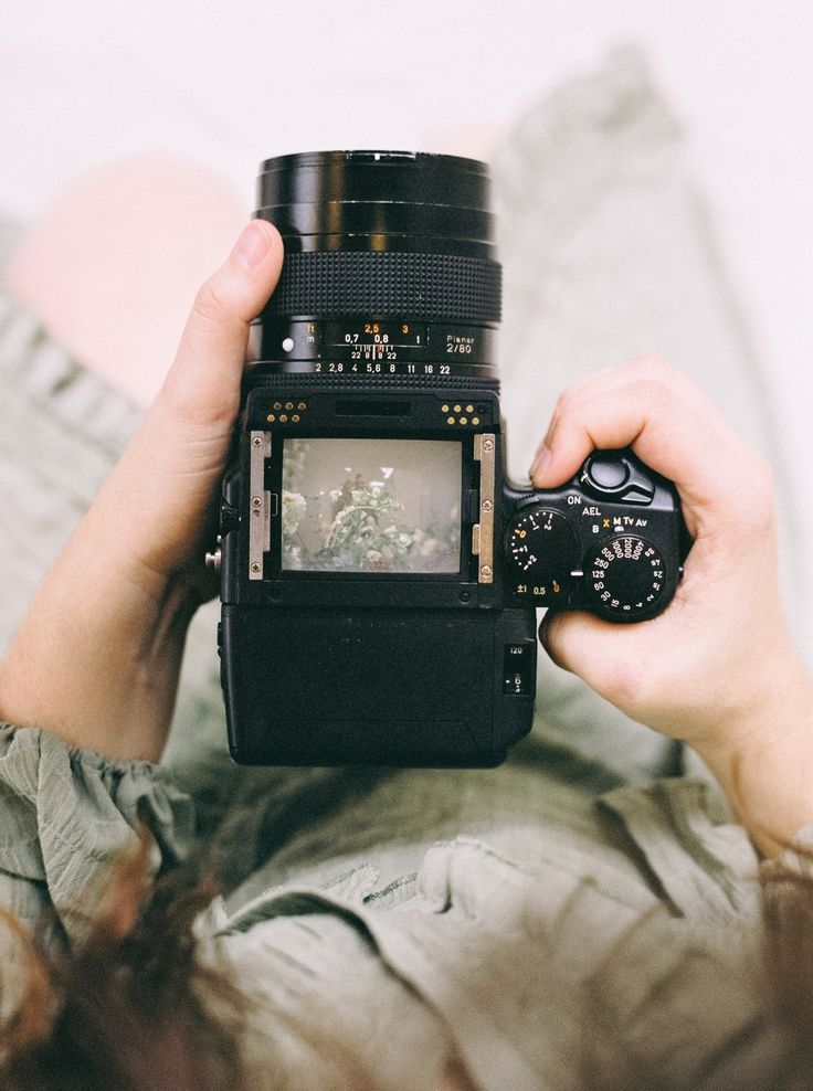 a person holding a camera up to their face with the lens in front of them