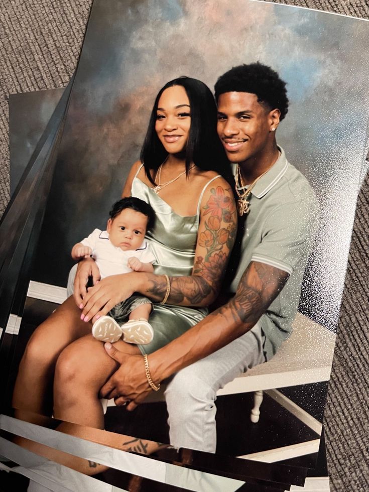 a man and woman sitting next to each other holding a baby