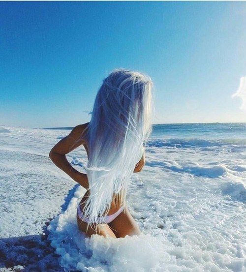 a woman with white hair sitting on the beach