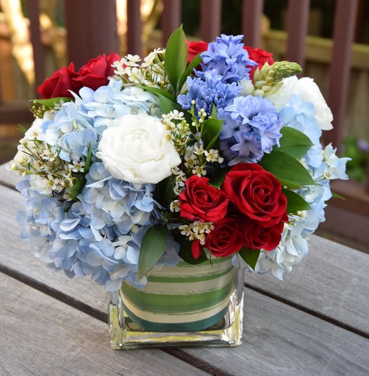 a vase filled with red, white and blue flowers on top of a wooden table