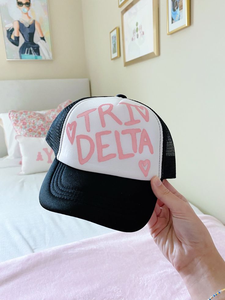 a person holding up a trucker hat with the word'try delta'written on it