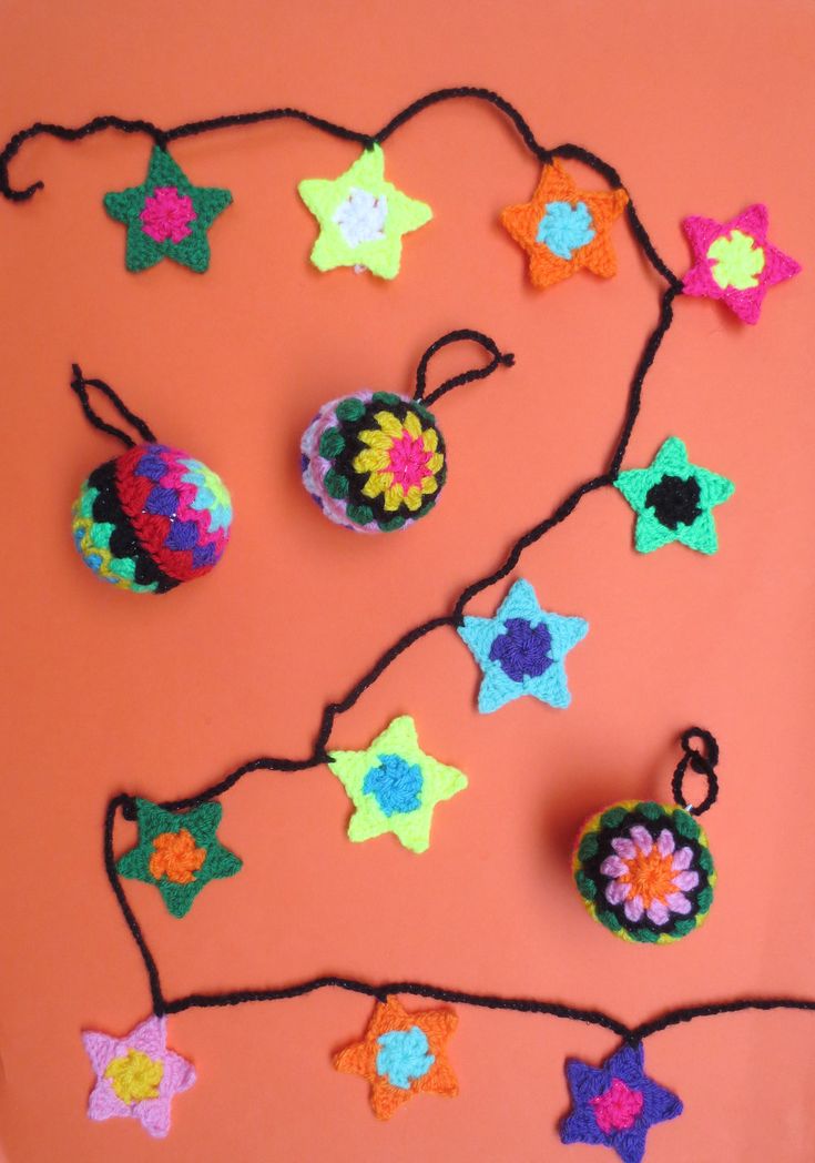 crocheted ornaments are hanging from a string on an orange surface with black cords