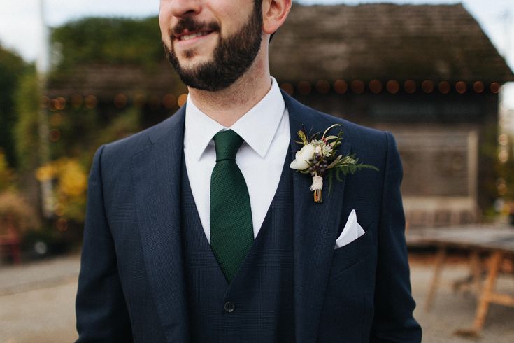 a man wearing a suit and tie with a flower in his lapel is smiling at the camera