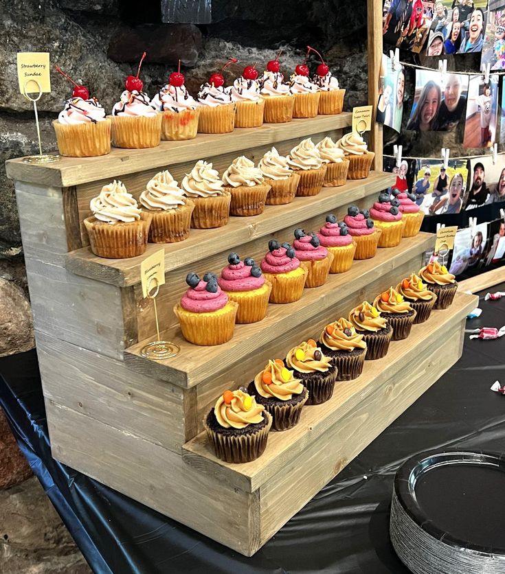 cupcakes are arranged on three tiered wooden stand