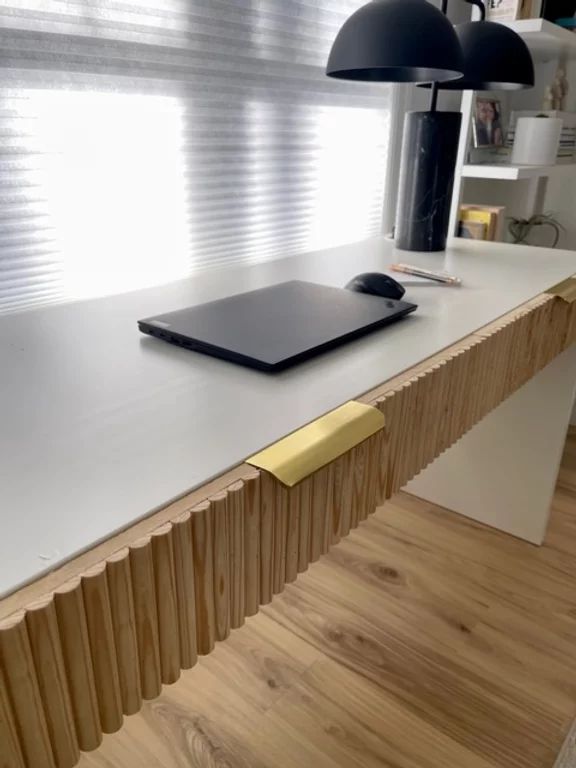 a laptop computer sitting on top of a wooden desk next to a lamp and window