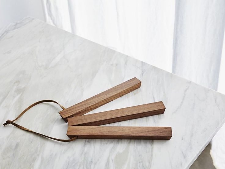 three pieces of wood sitting on top of a white table next to a brown cord