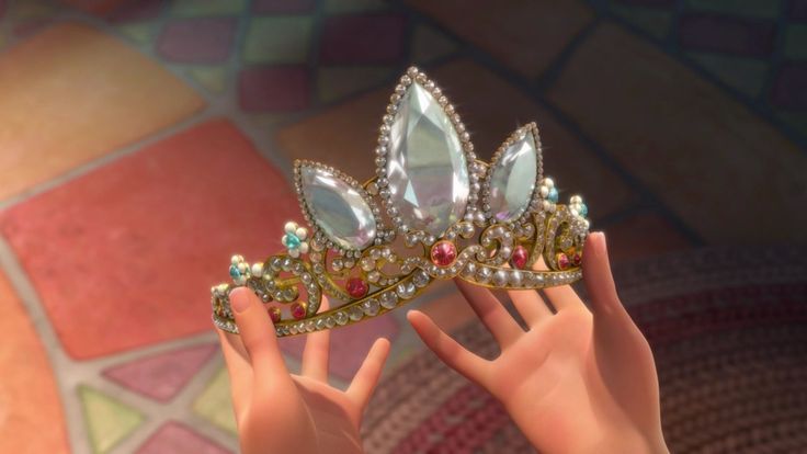 a close up of a person holding a tiara on their hand with other hands