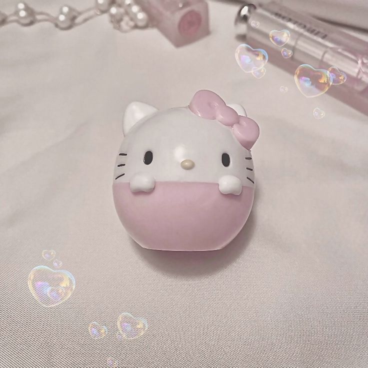 a hello kitty keychain is laying on a white sheet with bubbles around it