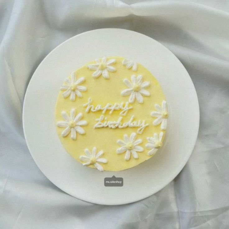 a white plate topped with a yellow and white frosted cake covered in icing