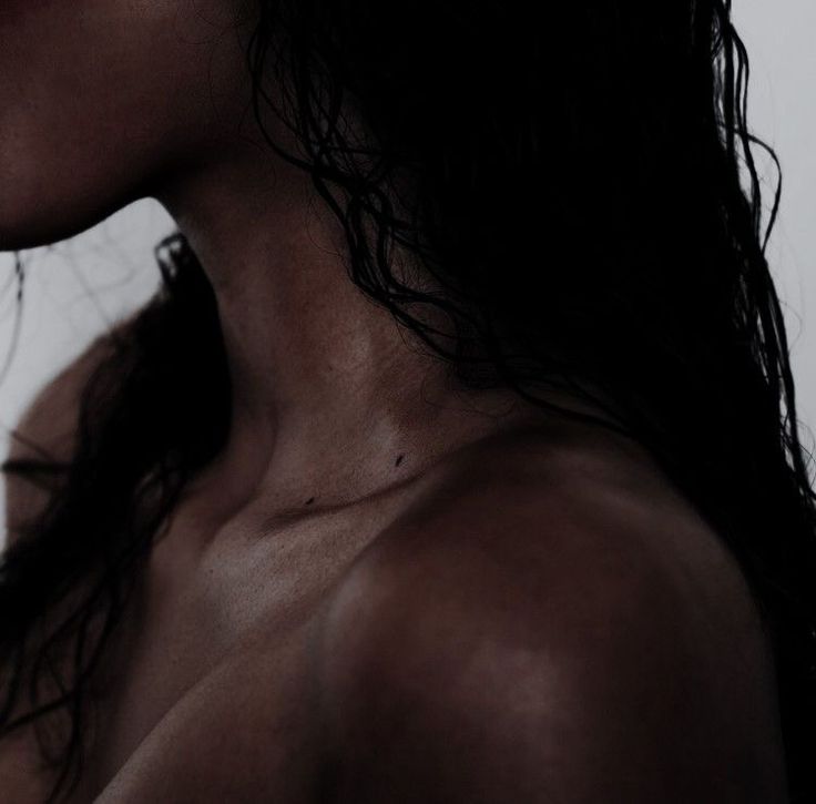 a close up of a woman's neck and shoulder with hair blowing in the wind