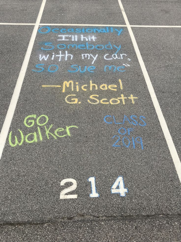 a parking lot with chalk writing on the asphalt and numbers painted on it in different colors