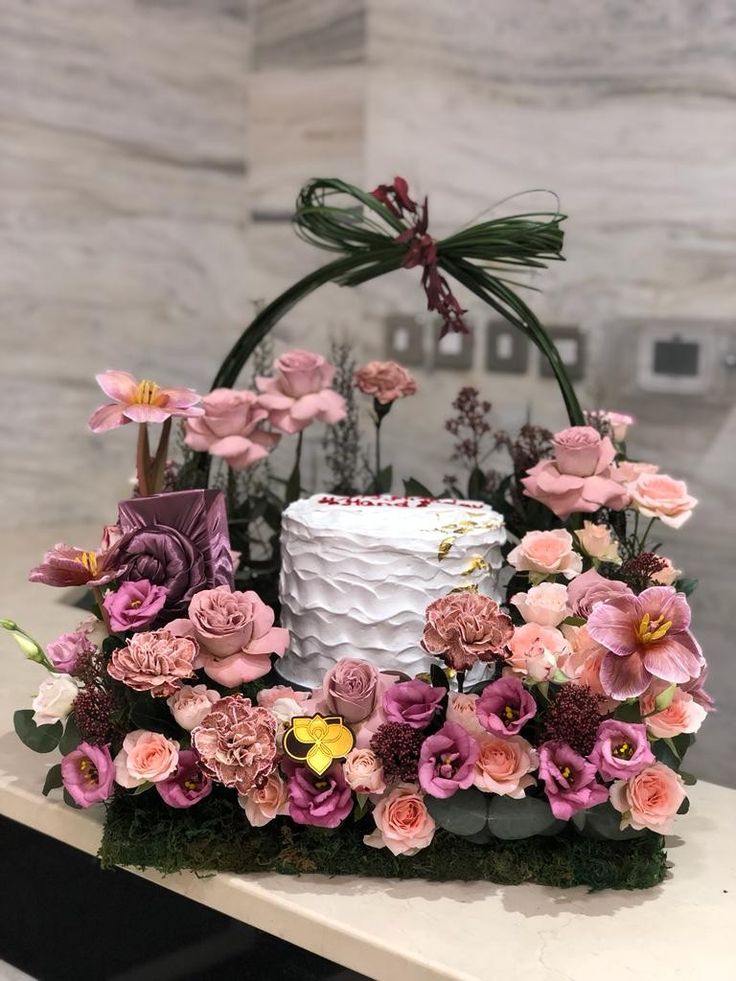 a white cake with pink flowers and greenery