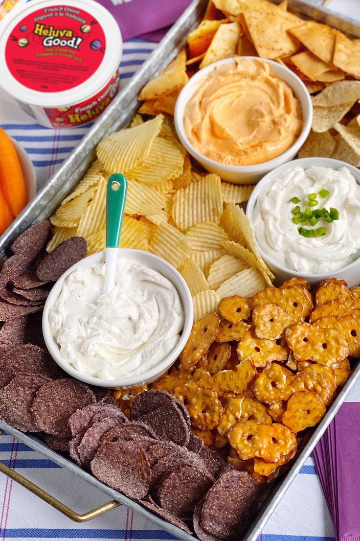 a tray filled with chips, dips and other food on top of a table