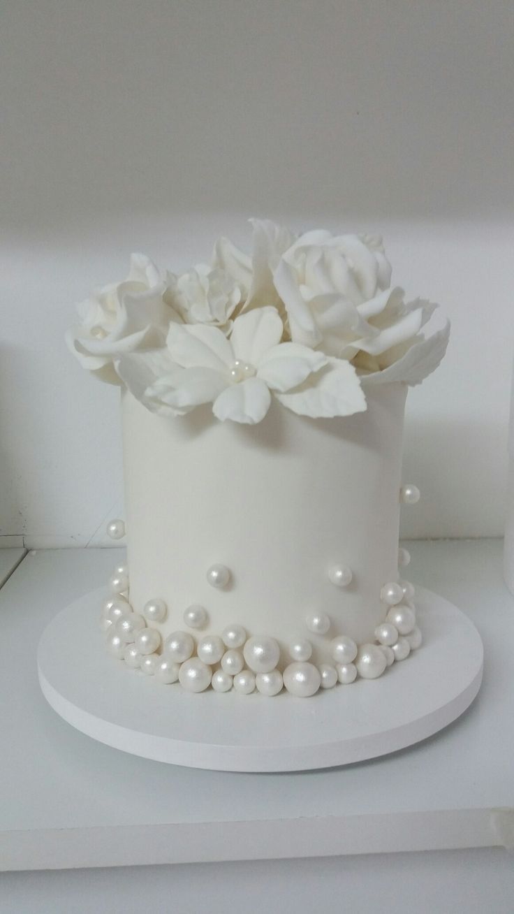 a white cake decorated with flowers and pearls