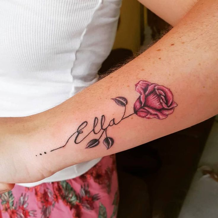 a woman's arm with a rose tattoo and the word eva written in cursive writing