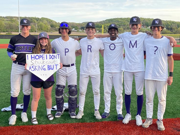 a group of people standing on top of a baseball field holding a sign that says prom