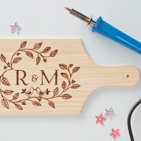 a personalized cutting board with flowers and leaves on it next to a blue pen