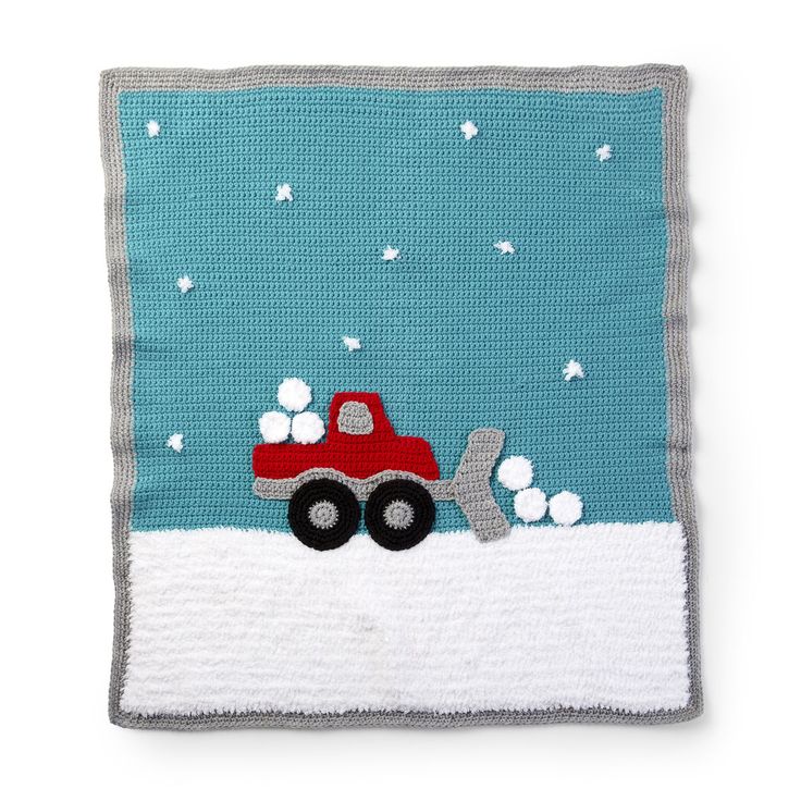 a crocheted blanket with a red truck on it and snowflakes in the background