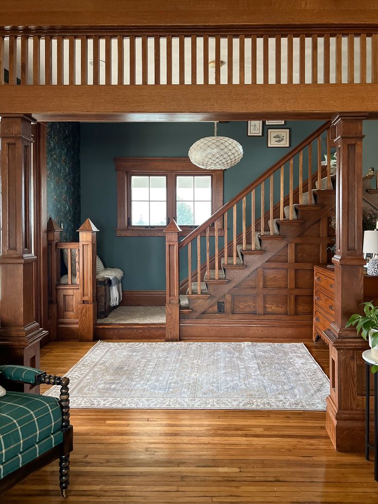 a living room filled with furniture next to a wooden stair case on top of a hard wood floor