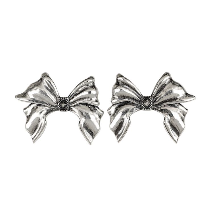 Our Bow Earrings expertly crafted in gleaming silver, emulate the elegance of a real bow. Inspired by the intricate details of the Pregomesh, these earrings feature crisply sculpted elements, capturing the essence of coquettish charm with a touch of boldness. White Gold Bow Earrings For Gift, Sterling Silver White Gold Earrings With Bow, White Gold Sterling Silver Earrings With Bow, White Gold Bow Earrings For Formal Occasions, White Gold Clip-on Earrings For Party, Elegant White Gold Earrings With Bow, Chic Silver Jewelry With Bow Tie Detail, Formal Silver Metal Earrings, White Gold Metal Earrings For Evening