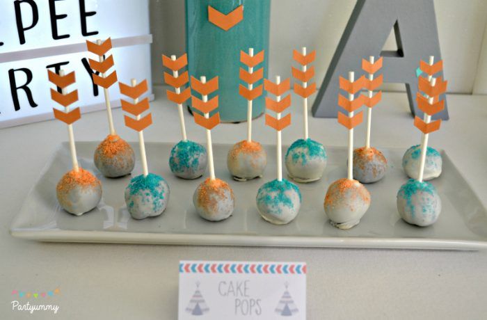 cake pops decorated with orange and blue frosting are on a tray next to an arrow sign