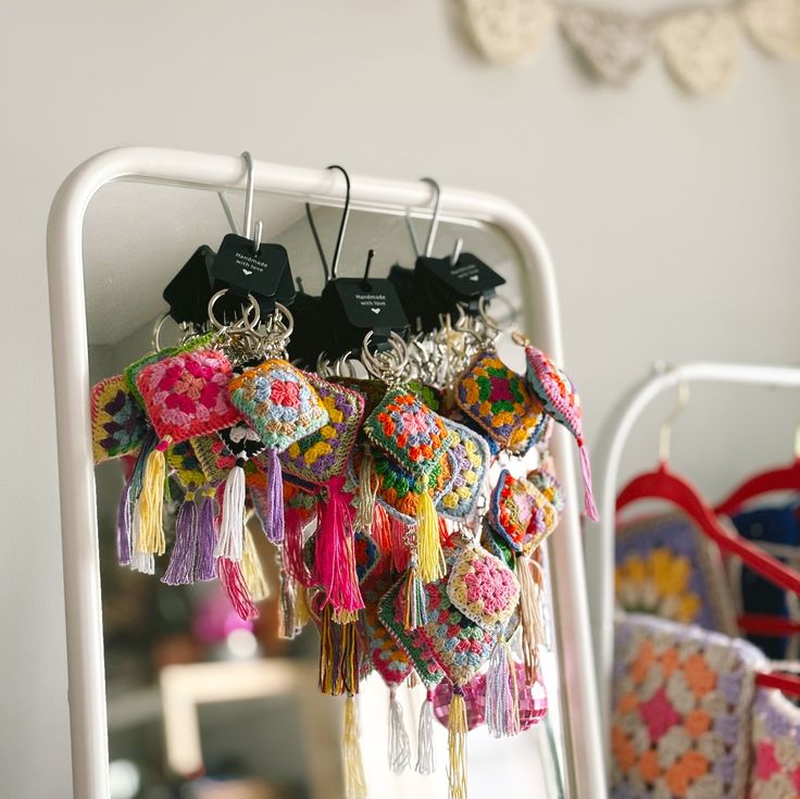 a rack filled with lots of tassels hanging from it's sides next to a mirror