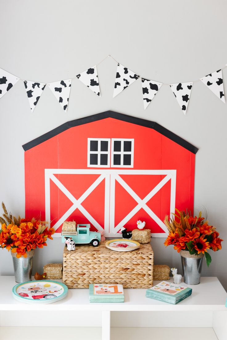 a red barn with black and white decorations on the roof, along with flowers in vases