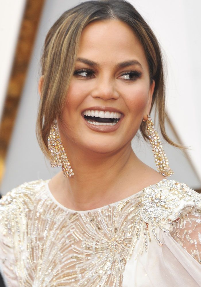 an image of a woman smiling on the oscars red carpet with her hair pulled back