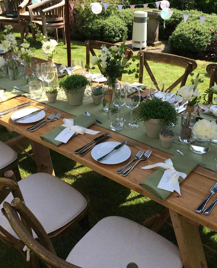 a long table set up with place settings and flowers on it for an outdoor dinner