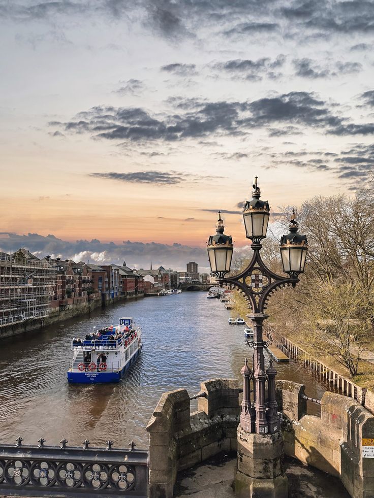 a boat traveling down a river next to a light pole and lamp post with street lights on it