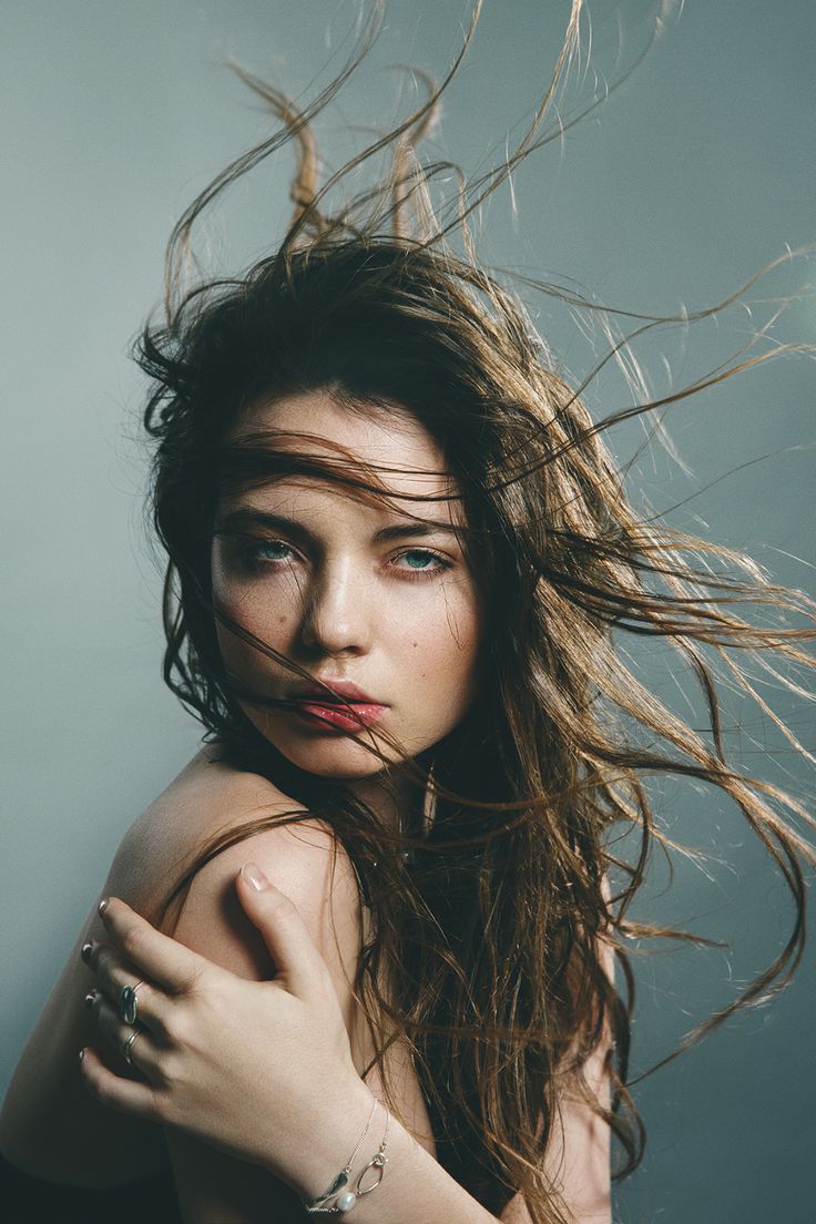 a woman with her hair blowing in the wind while posing for a photo studio shot