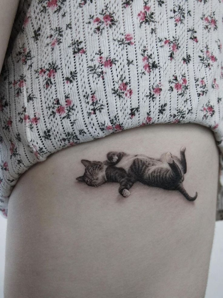 a woman's stomach with a cat tattoo on the side of her belly and two kittens in it