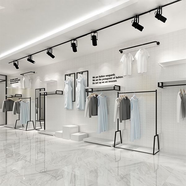 an empty clothing store with white walls and marble flooring, clothes hanging on racks