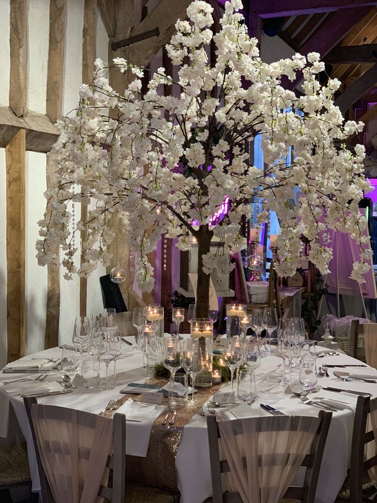 a dining table with white flowers and candles