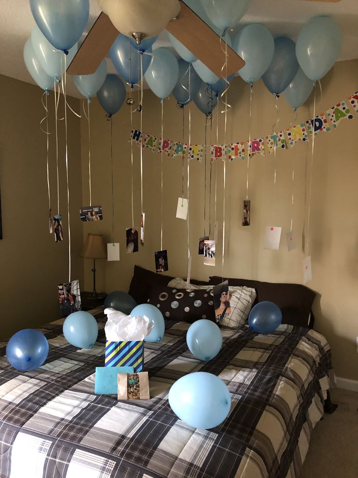 blue balloons are floating from the ceiling above a bed in a room with a checkered bedspread