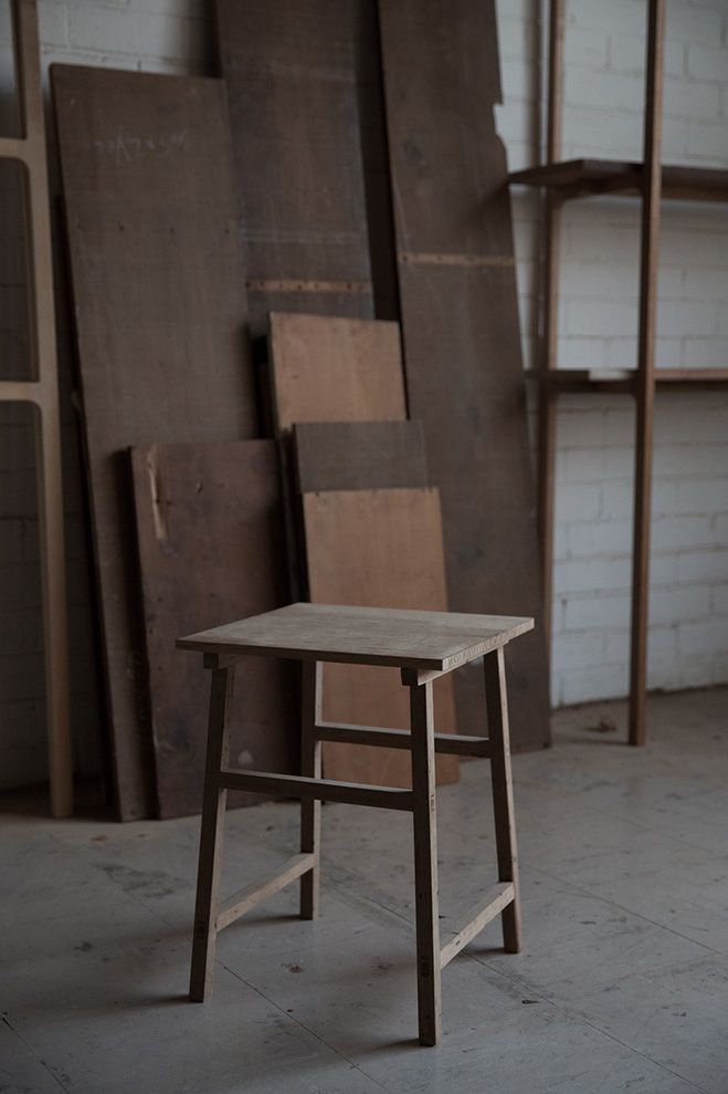 a small wooden chair sitting in front of a wall full of wood boards and shelves