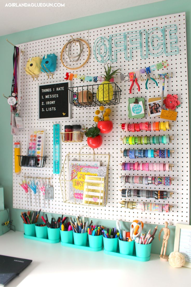 a white pegboard mounted to the side of a wall filled with crafting supplies