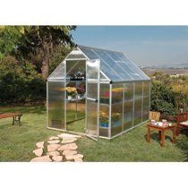 a small green house sitting on top of a lush green field next to a picnic table