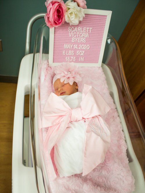 a baby in a crib with pink and white decorations