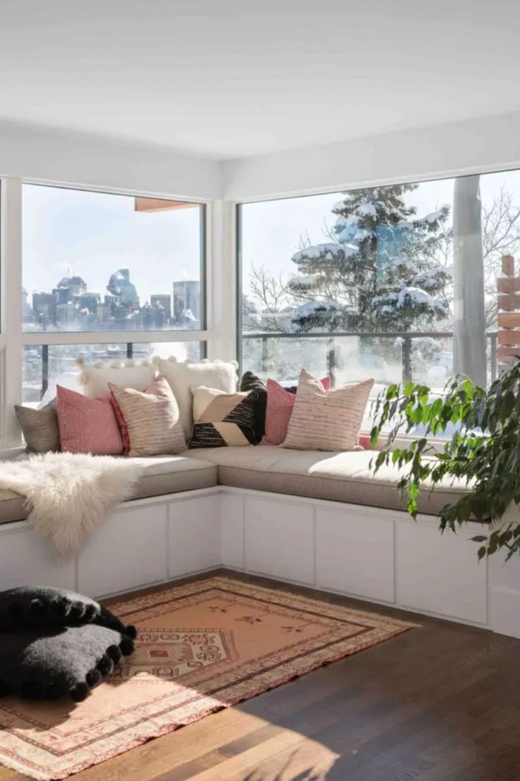 a living room filled with lots of furniture and large windows overlooking the snow covered city