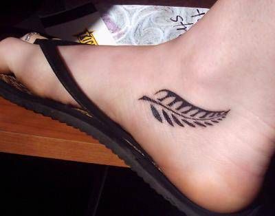 a woman's foot with a feather tattoo on it