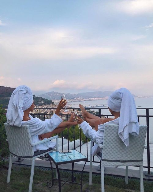 two women in robes sitting on white chairs